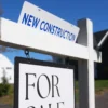 A row of suburban houses with for sale signs and a moving truck in a tight housing market
