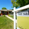 A house for sale sign in front of a suburban home as mortgage rates remain elevated