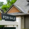 A for-sale sign outside a starter home in a residential neighborhood