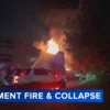 Fire crews respond to a burning apartment building with smoke and flames rising from the roof