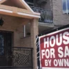 A row of suburban homes with a for-sale sign in front of one property