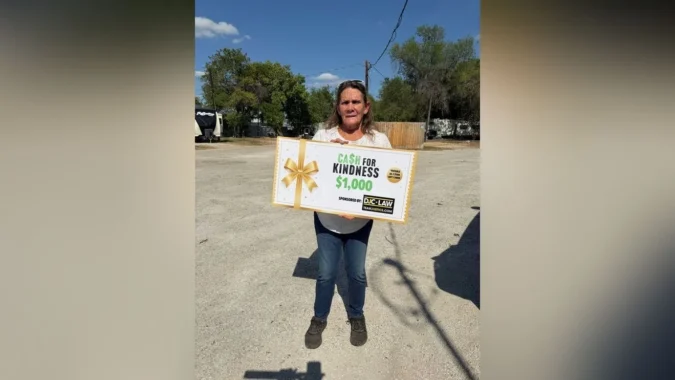 Two San Antonio women share an emotional moment beside a vehicle after a Cash for Kindness award