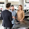 Rows of new cars at a dealership with signs highlighting monthly financing payments